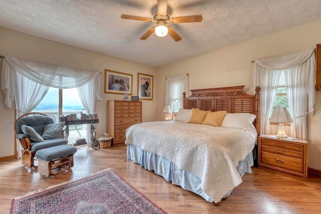 645 E Double Knob Dr, Hayesville, NC 28904 - bedroom with light wood finished floors, a textured ceiling, a ceiling fan, and baseboards