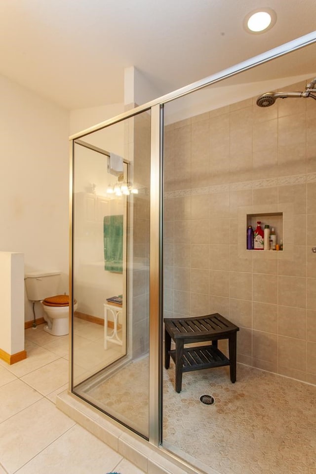 bathroom featuring tile patterned flooring, toilet, and a shower with shower door