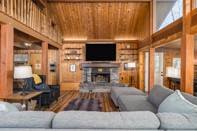 living room with hardwood / wood-style flooring, a wealth of natural light, a stone fireplace, and wooden walls