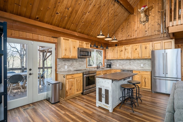 kitchen featuring appliances with stainless steel finishes, french doors, beam ceiling, a center island, and dark hardwood / wood-style floors