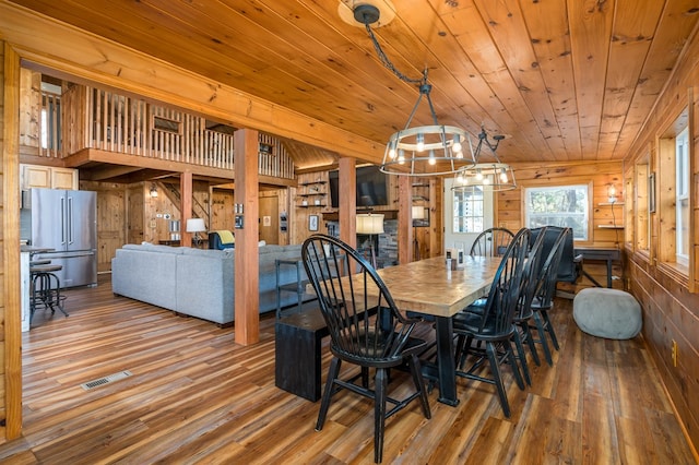 dining space featuring hardwood / wood-style flooring, wooden ceiling, and wood walls