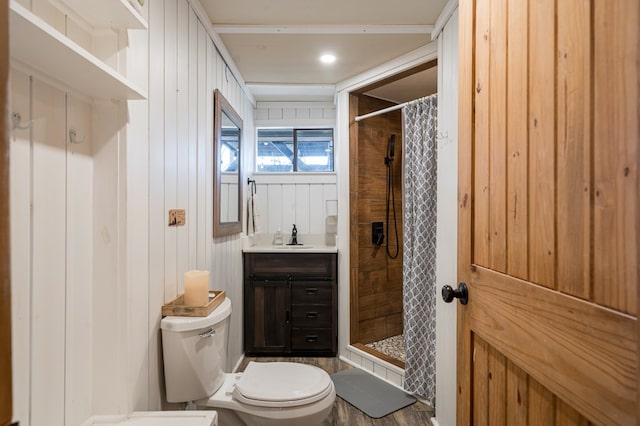 bathroom featuring vanity, toilet, walk in shower, and wooden walls