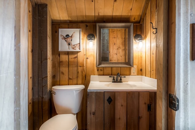 bathroom with vanity, toilet, wood walls, and wood ceiling