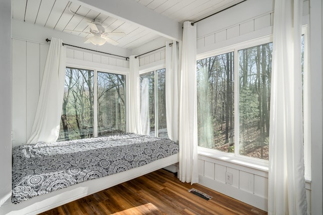 bedroom featuring multiple windows, beam ceiling, dark hardwood / wood-style floors, and ceiling fan