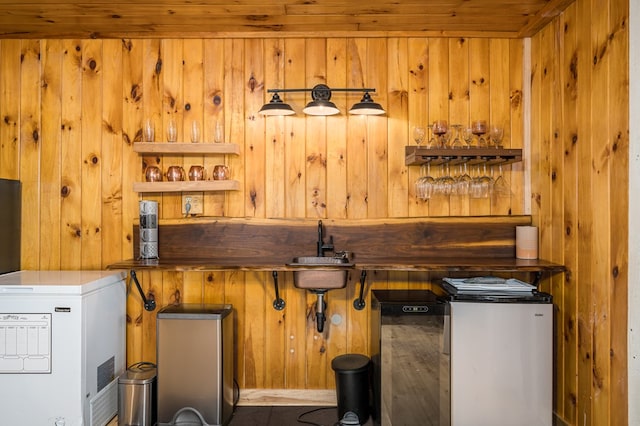 bar with wood walls, sink, and fridge