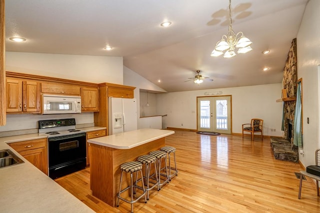 kitchen with white appliances, a kitchen breakfast bar, light wood-style floors, light countertops, and french doors