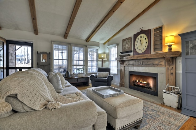 living area with vaulted ceiling with beams, a fireplace, and wood finished floors