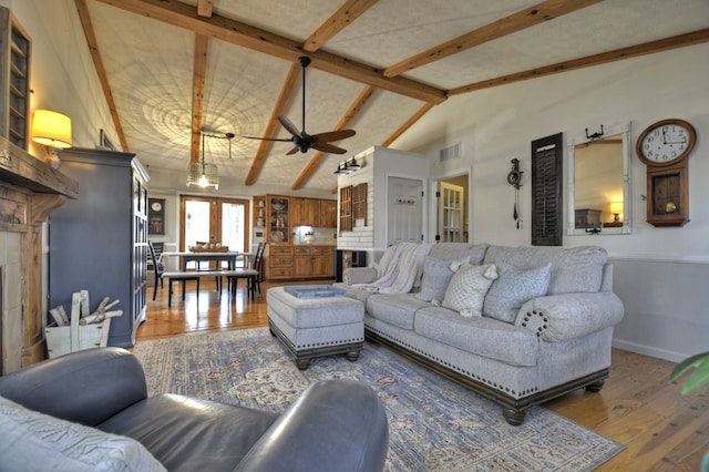 living area with french doors, visible vents, lofted ceiling with beams, wood finished floors, and baseboards