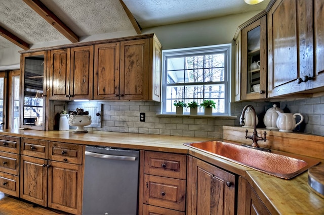 kitchen with butcher block countertops, a sink, backsplash, and stainless steel dishwasher