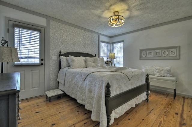 bedroom with a textured ceiling, baseboards, and hardwood / wood-style floors