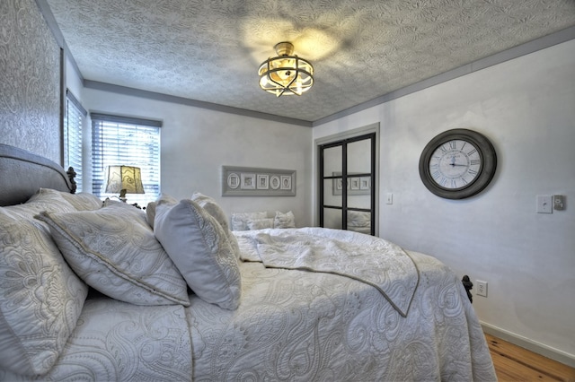 bedroom featuring a textured ceiling, baseboards, and wood finished floors