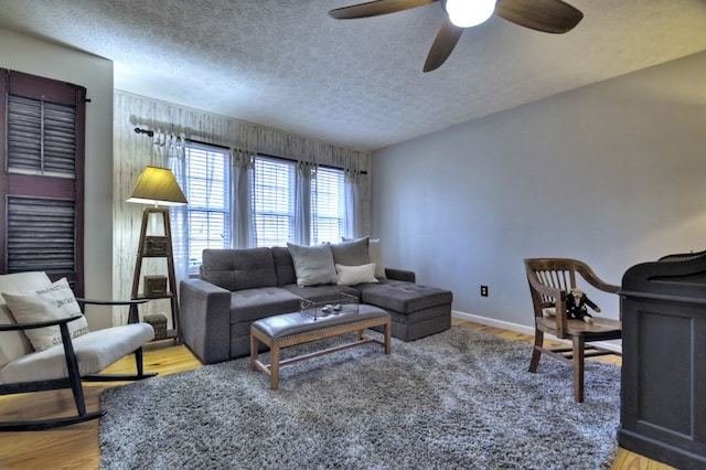 living room featuring light wood-style floors, ceiling fan, and a textured ceiling