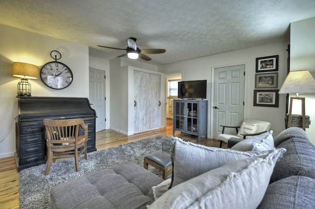 living room featuring a textured ceiling, wood finished floors, a ceiling fan, and baseboards