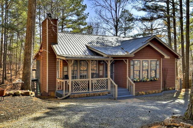 rustic home featuring covered porch, metal roof, a chimney, and a standing seam roof