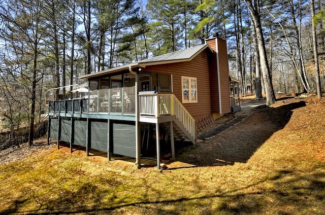 rear view of house featuring a sunroom, a chimney, stairway, and metal roof