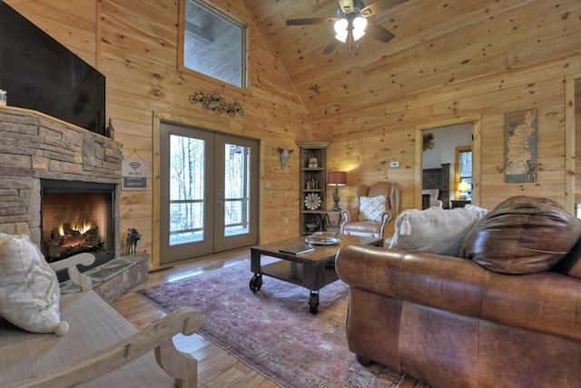 living room with wood walls, hardwood / wood-style flooring, a fireplace, and high vaulted ceiling