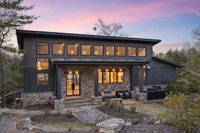 back house at dusk with an outdoor living space and a patio