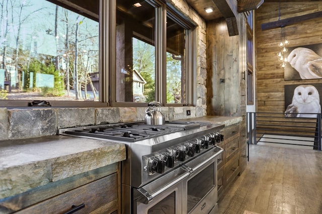 kitchen with dark hardwood / wood-style floors, range with two ovens, and wooden walls