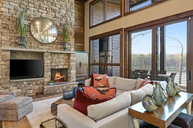 living room with a towering ceiling, hardwood / wood-style flooring, and a stone fireplace