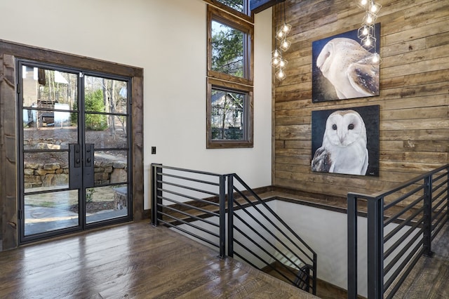 stairway with wood walls, french doors, and hardwood / wood-style flooring