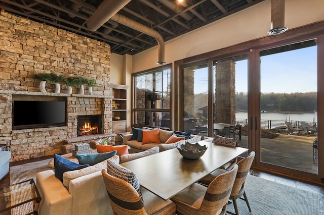 interior space featuring a fireplace, a towering ceiling, and a water view