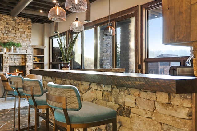 bar featuring a fireplace, beam ceiling, hanging light fixtures, and a healthy amount of sunlight