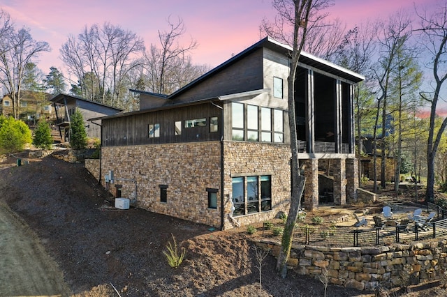 property exterior at dusk featuring a sunroom