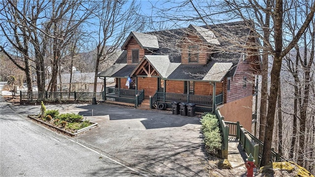 view of front of property featuring a porch, driveway, and a shingled roof