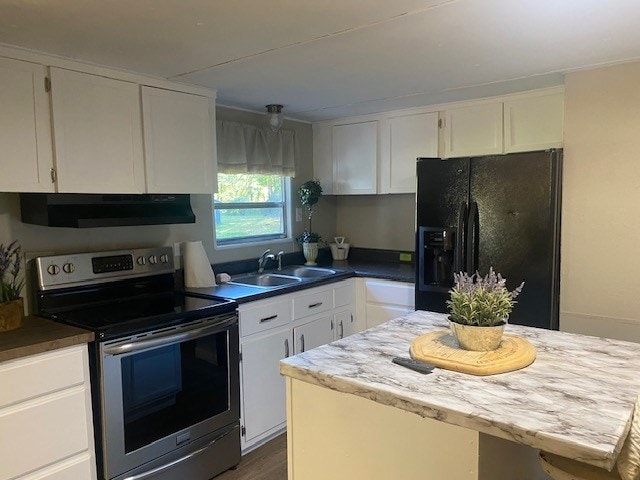 kitchen featuring stainless steel range with electric stovetop, sink, black fridge, and white cabinets