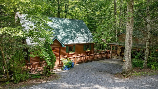 77 Old Covered Bridge Rd, Cherry Log, GA 30522 - view of front of home with a deck, a metal roof, faux log siding, a forest view, and gravel driveway