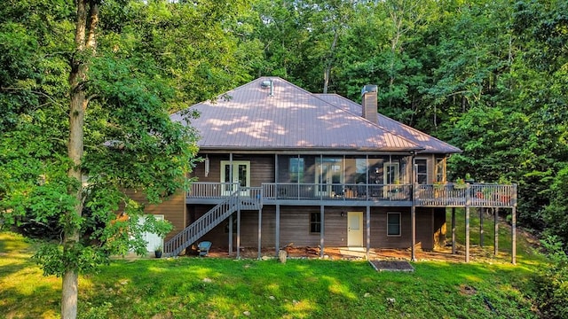 rear view of house featuring a lawn, a sunroom, stairs, a deck, and french doors