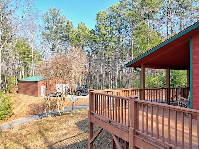 wooden terrace with an outbuilding and a view of trees