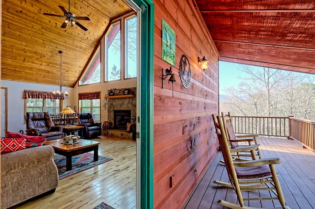 exterior space featuring a fireplace, hardwood / wood-style flooring, wood ceiling, and high vaulted ceiling