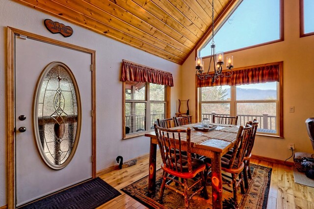 dining room featuring baseboards, vaulted ceiling, wood ceiling, light wood-style floors, and a notable chandelier