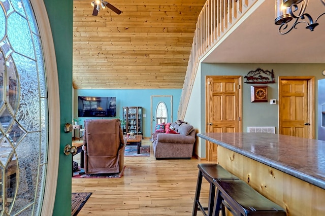 living area with visible vents, a towering ceiling, a ceiling fan, and light wood finished floors