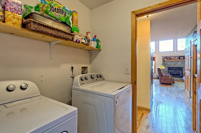 laundry area with a fireplace, laundry area, washing machine and dryer, and light wood-style floors