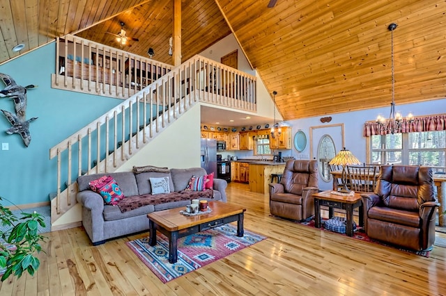 living room featuring stairway, high vaulted ceiling, wood ceiling, ceiling fan with notable chandelier, and light wood-type flooring