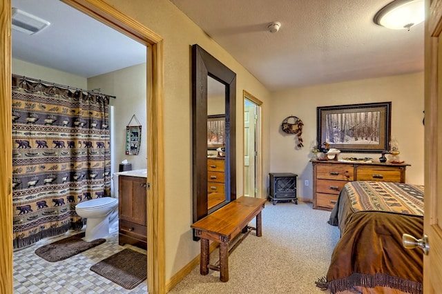 bedroom featuring light carpet, baseboards, visible vents, and a textured ceiling