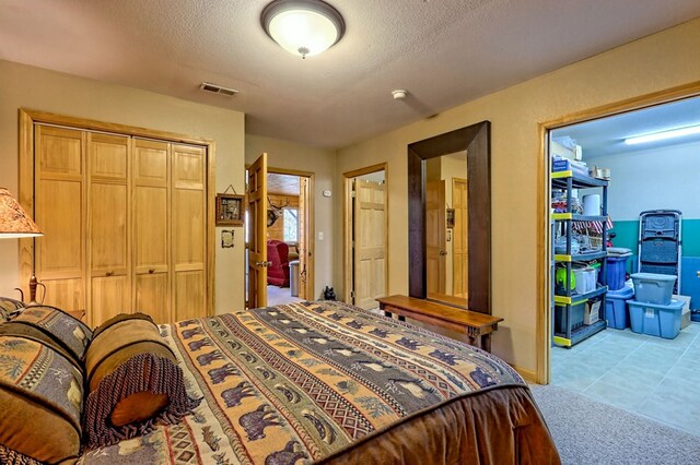 bedroom featuring a closet, visible vents, light colored carpet, and a textured ceiling