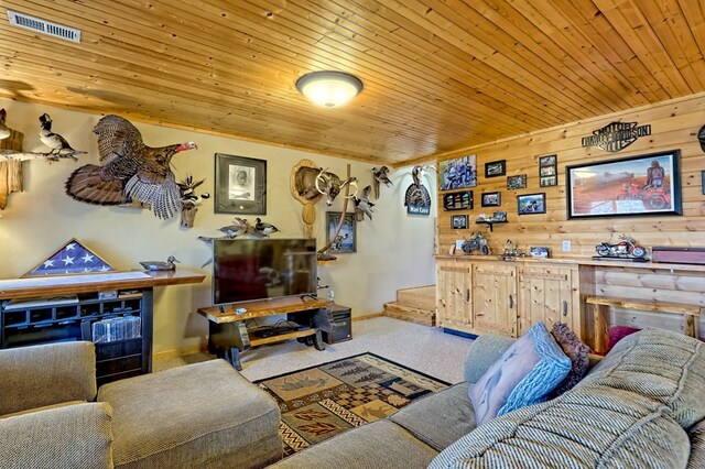 carpeted living area with wooden walls, wood ceiling, visible vents, and baseboards