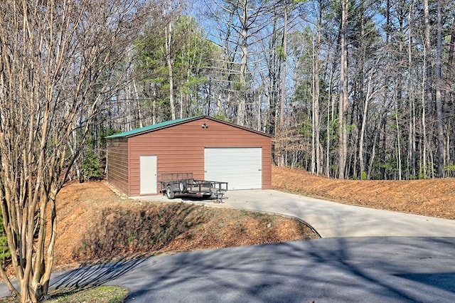 detached garage featuring a wooded view and concrete driveway