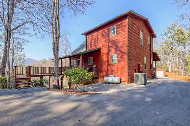 view of home's exterior featuring central air condition unit, a garage, a wooden deck, and an outdoor structure