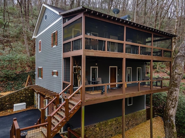 back of property with a deck, stairway, and a sunroom