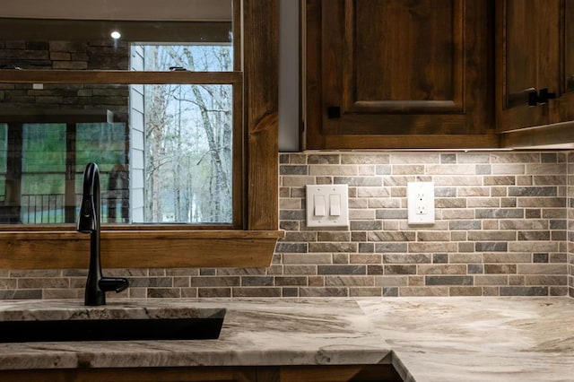 room details with sink, dark brown cabinets, and backsplash