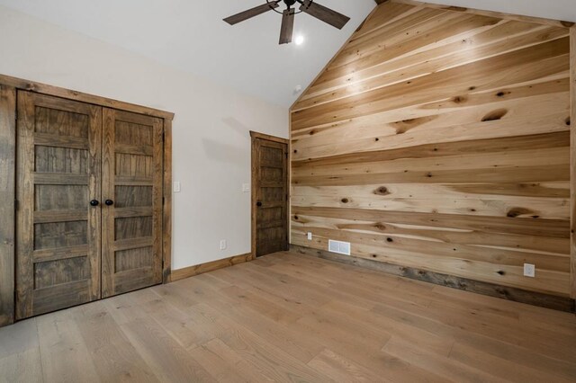 interior space with light hardwood / wood-style flooring, high vaulted ceiling, wooden walls, and ceiling fan