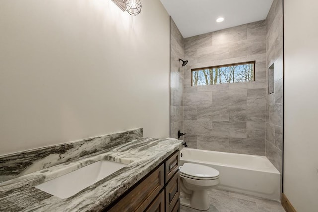 full bathroom featuring tiled shower / bath, vanity, and toilet