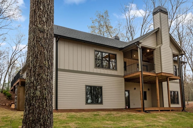 rear view of property featuring a yard and a balcony