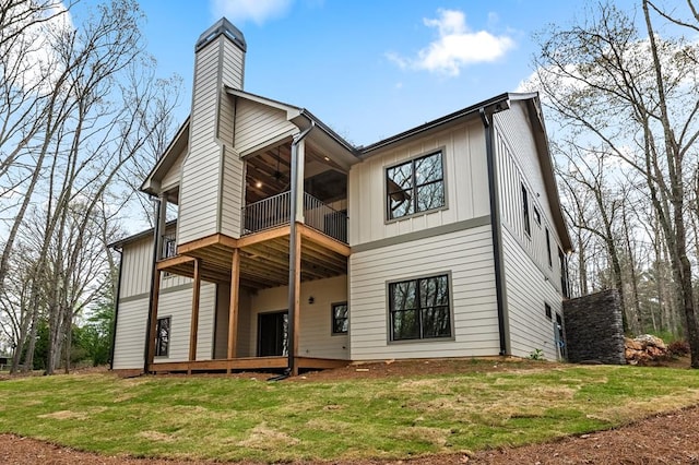 rear view of house featuring a balcony and a yard