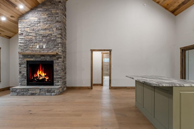 unfurnished living room with high vaulted ceiling, a fireplace, wood ceiling, and light hardwood / wood-style floors