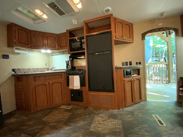 kitchen featuring sink, dark tile patterned floors, and black appliances